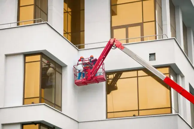 professionals standing on a painting the exterior of white commercial building