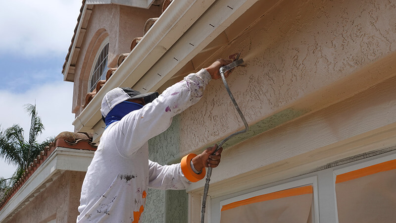 a residential house with workers painting the exterior walls