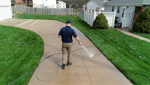 An individual using a pressure washer to clean a pathway